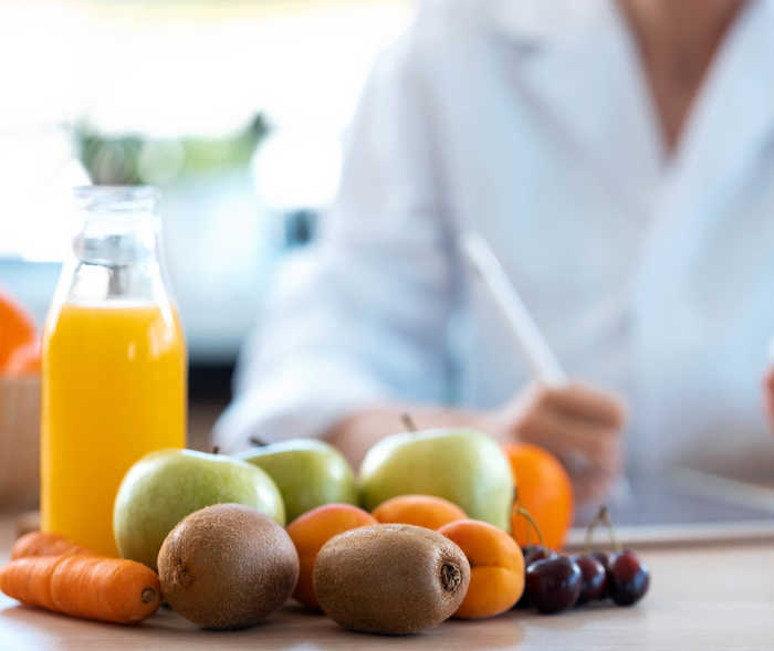 Leben mit NET: Auf dem Tisch einer Ärztin liegen gesunde Lebensmitel wie Obst und Gemüse Leben mit NET: Auf dem Tisch einer Ärztin liegen gesunde Lebensmitel wie Obst und Gemüse