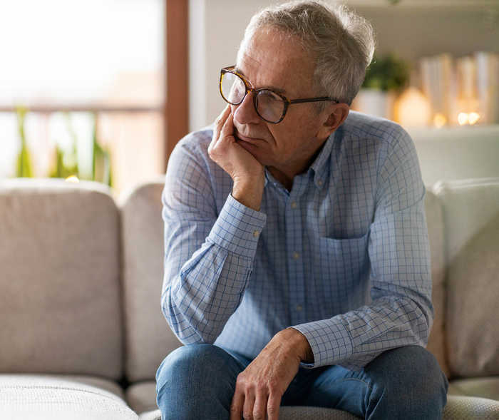 Leben mit NET: Ein Patient, der gerade seine Diagnose bekommt hat, sitzt nachdenklich auf einem Sofa Leben mit NET: Ein Patient, der gerade seine Diagnose bekommt hat, sitzt nachdenklich auf einem Sofa