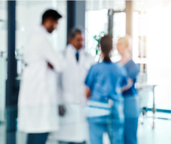Leben mit NET: Ein verschwommenes Bild, das Ärzte und Pflegepersonal im Gespräch zeigt Leben mit NET: Ein verschwommenes Bild, das Ärzte und Pflegepersonal im Gespräch zeigt