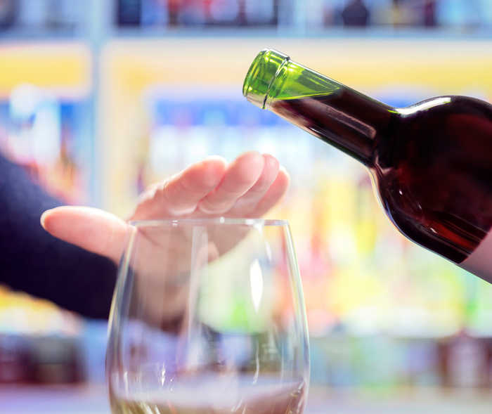 Leben mit NET: Eine Frau lehnt das Einschenken von Rotwein in ihr Glas ab