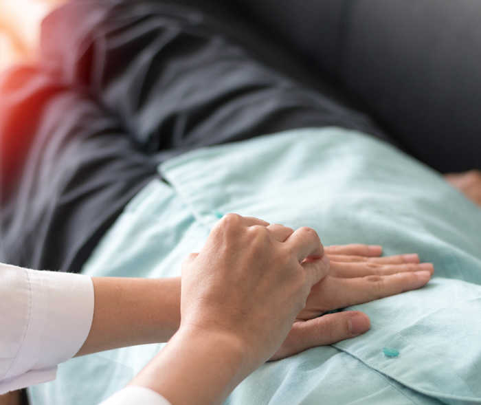 Leben mit NET: Eine Frau legt ihre Hände auf den Bauch eines Patienten. Leben mit NET: Eine Frau legt ihre Hände auf den Bauch eines Patienten.