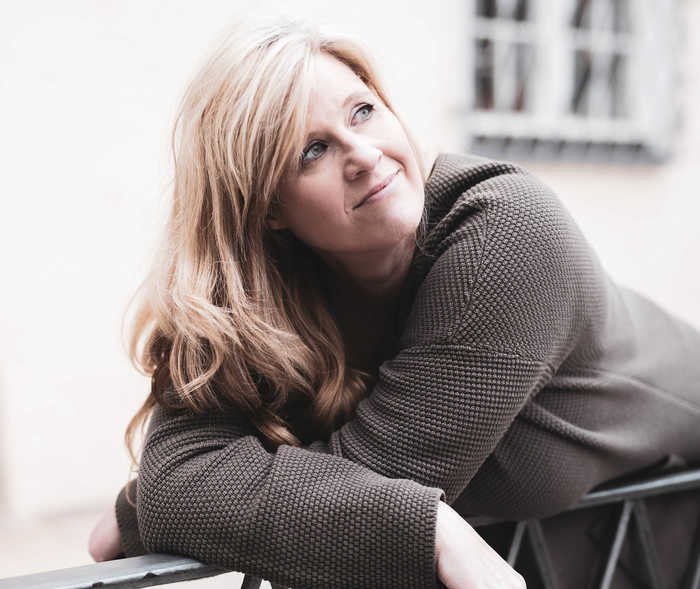 Leben mit NET: Eine Frau stützt sich auf ein Geländer und schaut gelassen über ihre linke Schulter Leben mit NET: Eine Frau stützt sich auf ein Geländer und schaut gelassen über ihre linke Schulter