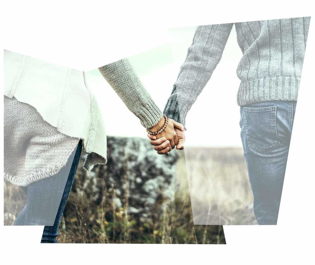 Ein Paar spaziert Hand in Hand auf einer Wiese