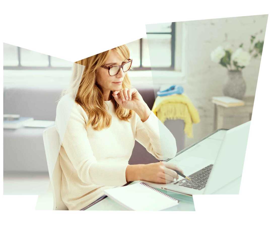 Blondhaarige Frau liest etwas auf ihrem Laptop