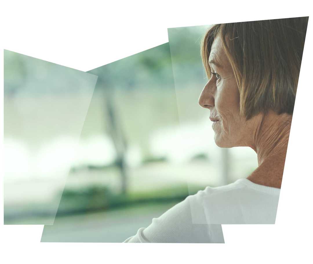 Dunkelhaarige Frau schaut aus dem Fenster