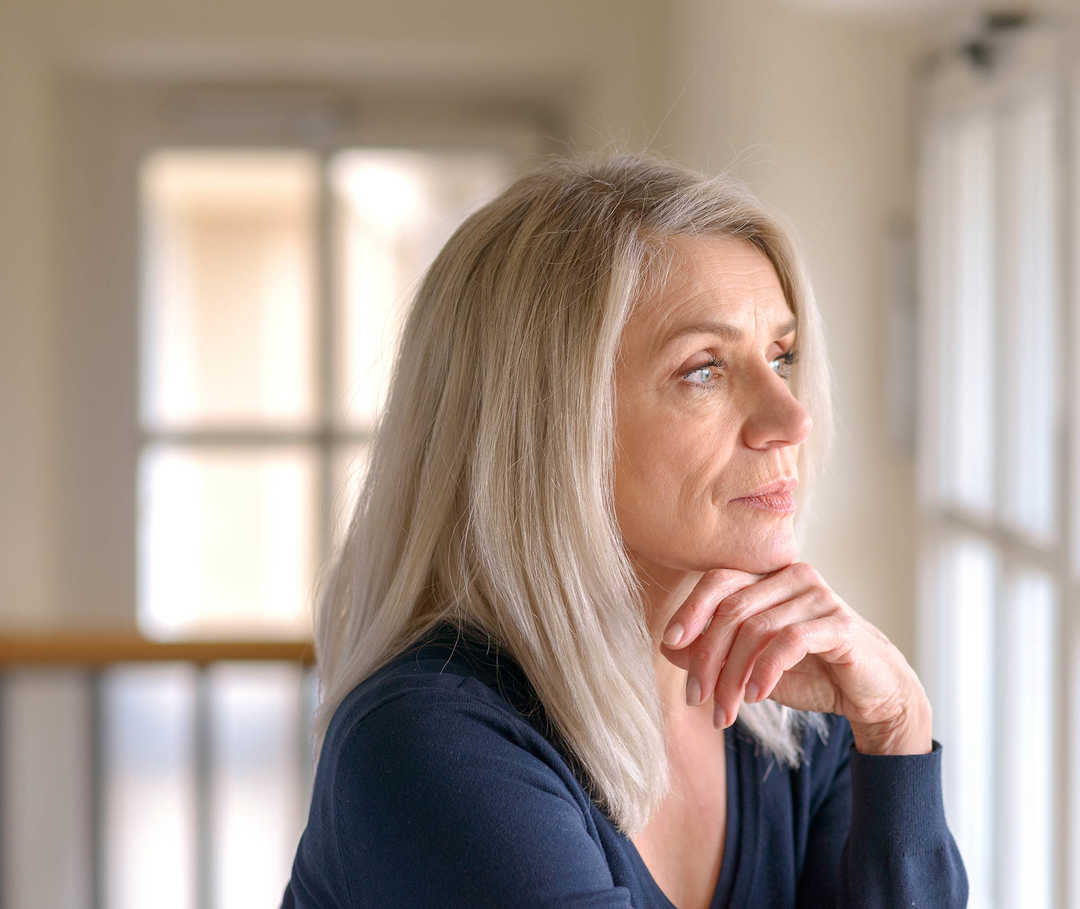 Leben mit NET: Eine nachdenkliche Frau schaut aus dem Fenster