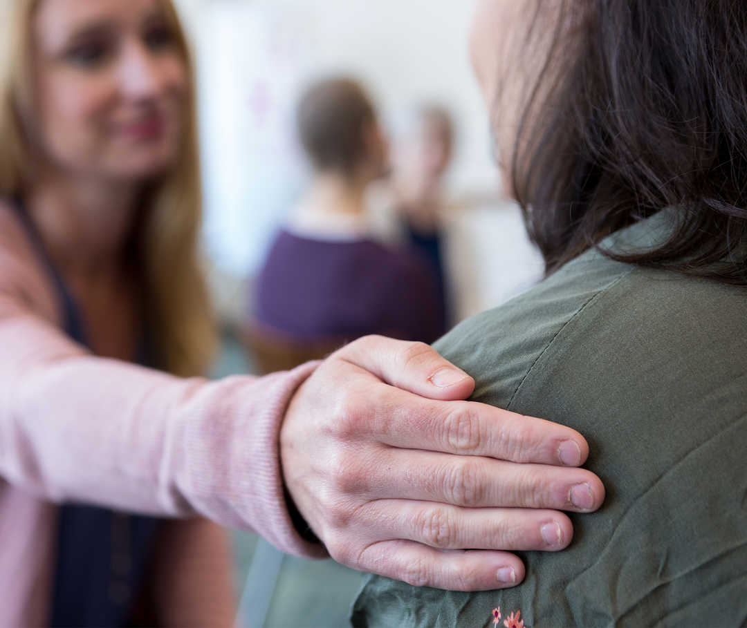 Leben mit NET: Eine Frau legt ihrer Haushaltshilfe dankbar die Hand auf die Schulter